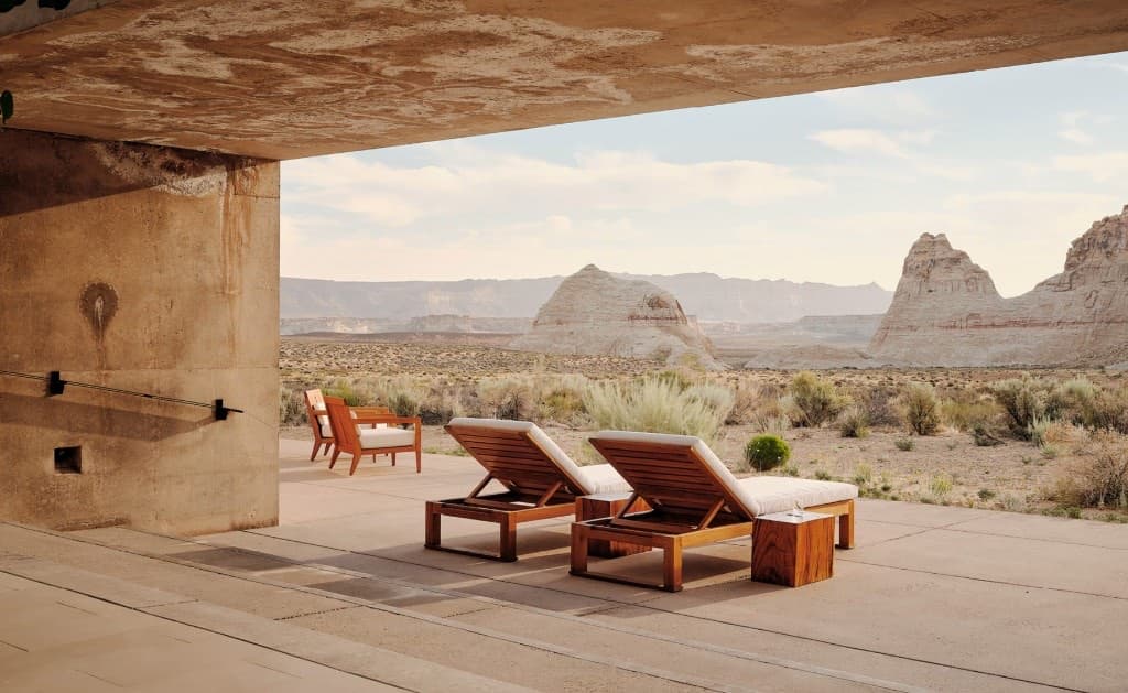 A sheltered terrace at Amangiri looking out over the Utah desert, with wooden lounge chairs facing the mesas